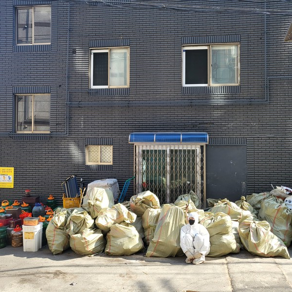 저장강박증 가구의 모아 두었던 쓰레기를 치운 자원봉사자가 쓰레기 더미 앞에서 잠시 쉬고 있다.(사진=인천미추홀구청)