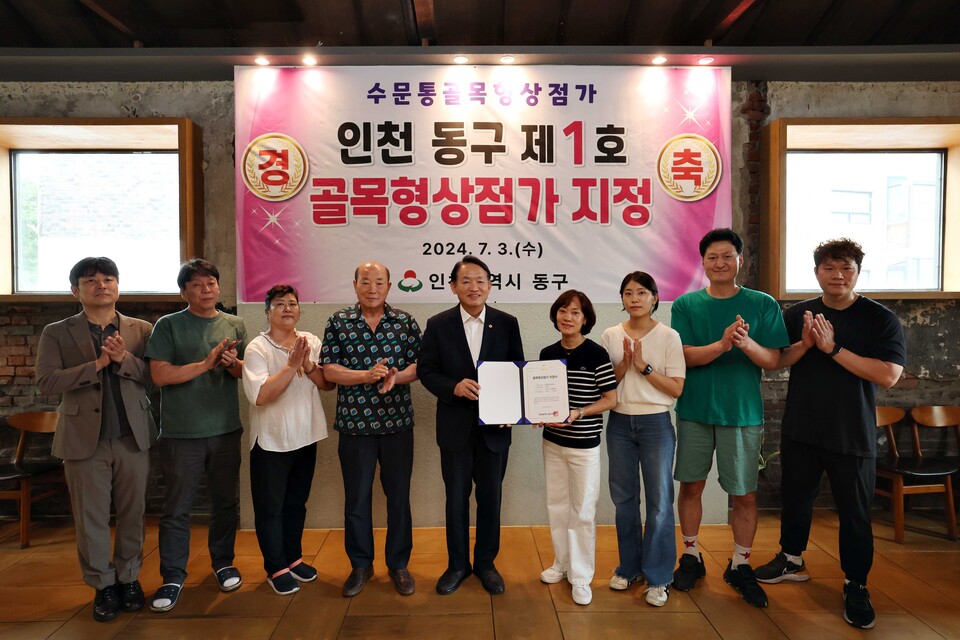 김찬진 동구청장(왼쪽에서 다섯번째)이 이날 수문통 지역 상인 20여명이 참석한 가운데 제1호 골목형상점가 지정서를 전달하고 기념촬영을 하고 있다.(사진=인천동구)