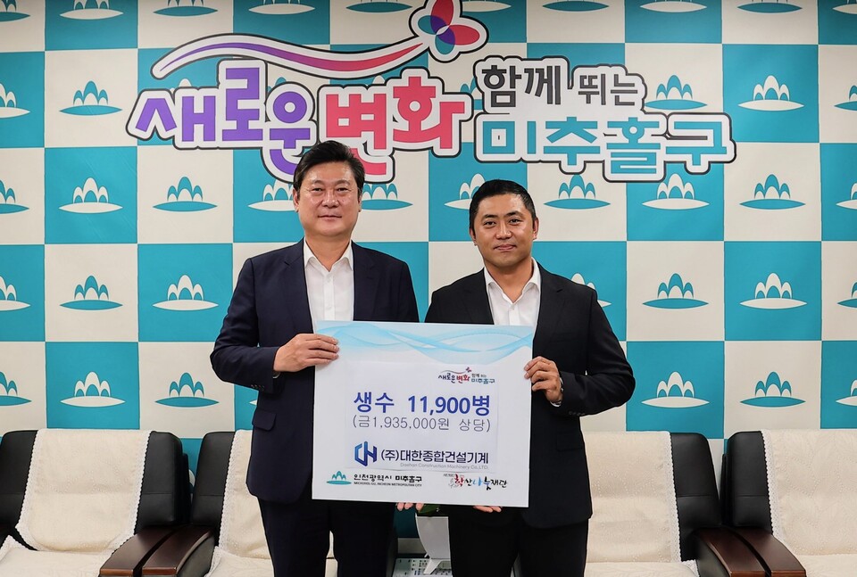 이영훈 인천미추홀구청장(왼쪽)이 대한종합건설기계 정광조 대표이사로부터 생수를 전달받고 기념촬영을 하고 있다.(사진=인천미추홀구)