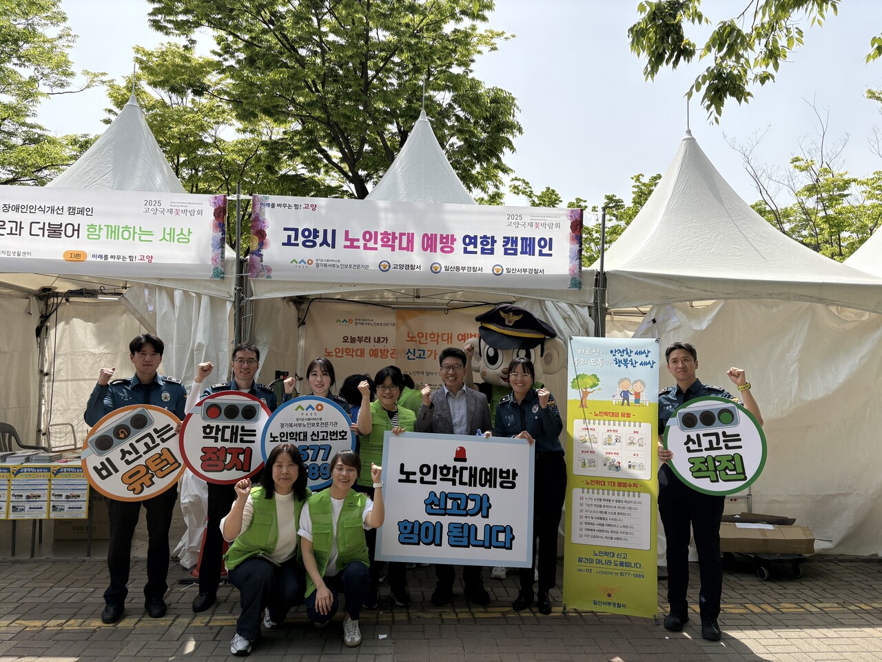경기북서부노인보호전문기관 한귀영 관장(뒷줄 왼쪽 네 번째) 및 관계자들이 고양국제꽃박람회에서 노인학대 예방 캠페인을 실시하고 있다. (사진=경기북서부노인보호전문기관)